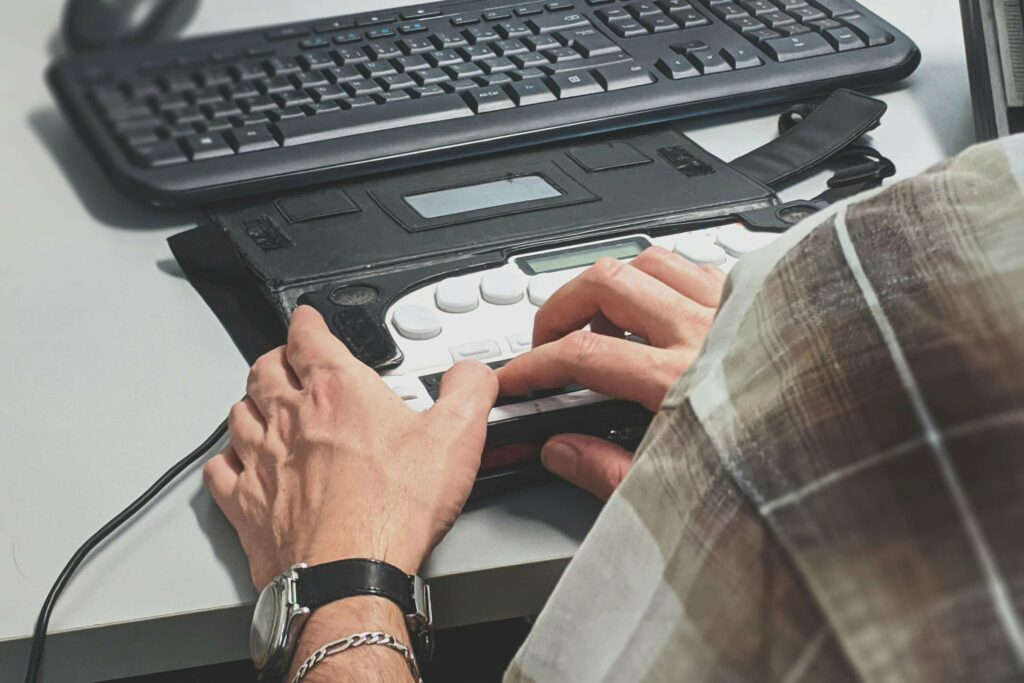 Person nutzt Braillezeile und Tastatur zur barrierefreien Webnavigation