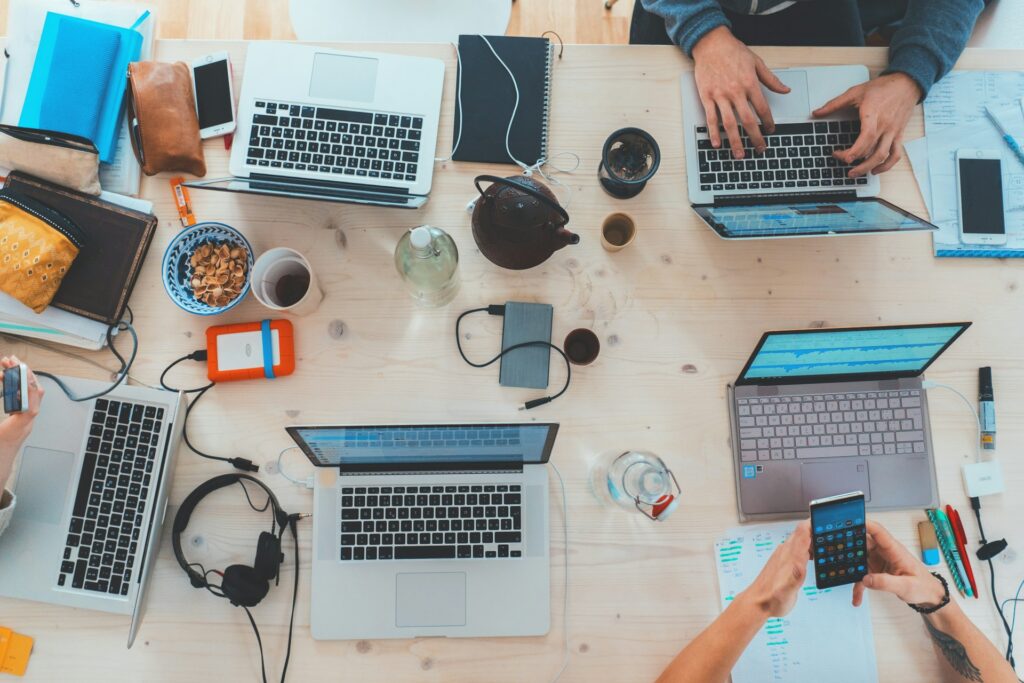 Bild von oben von Personen die mit Laptops an Marketingthemen arbeiten