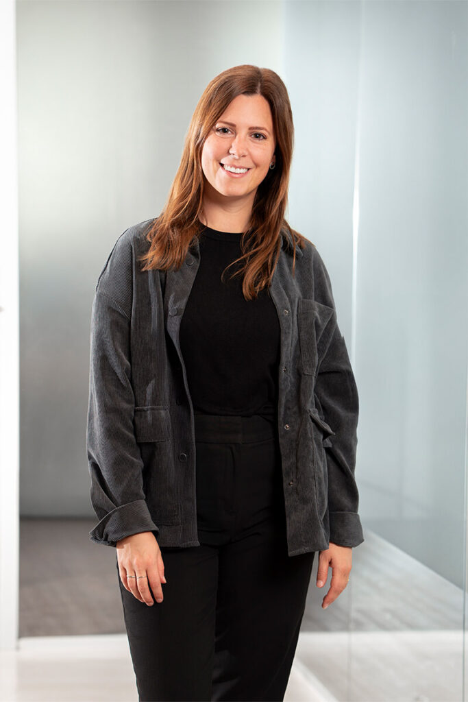 Brand Designerin Nicole mit glattem Haar, dunklem Blazer und sympathischem Blick